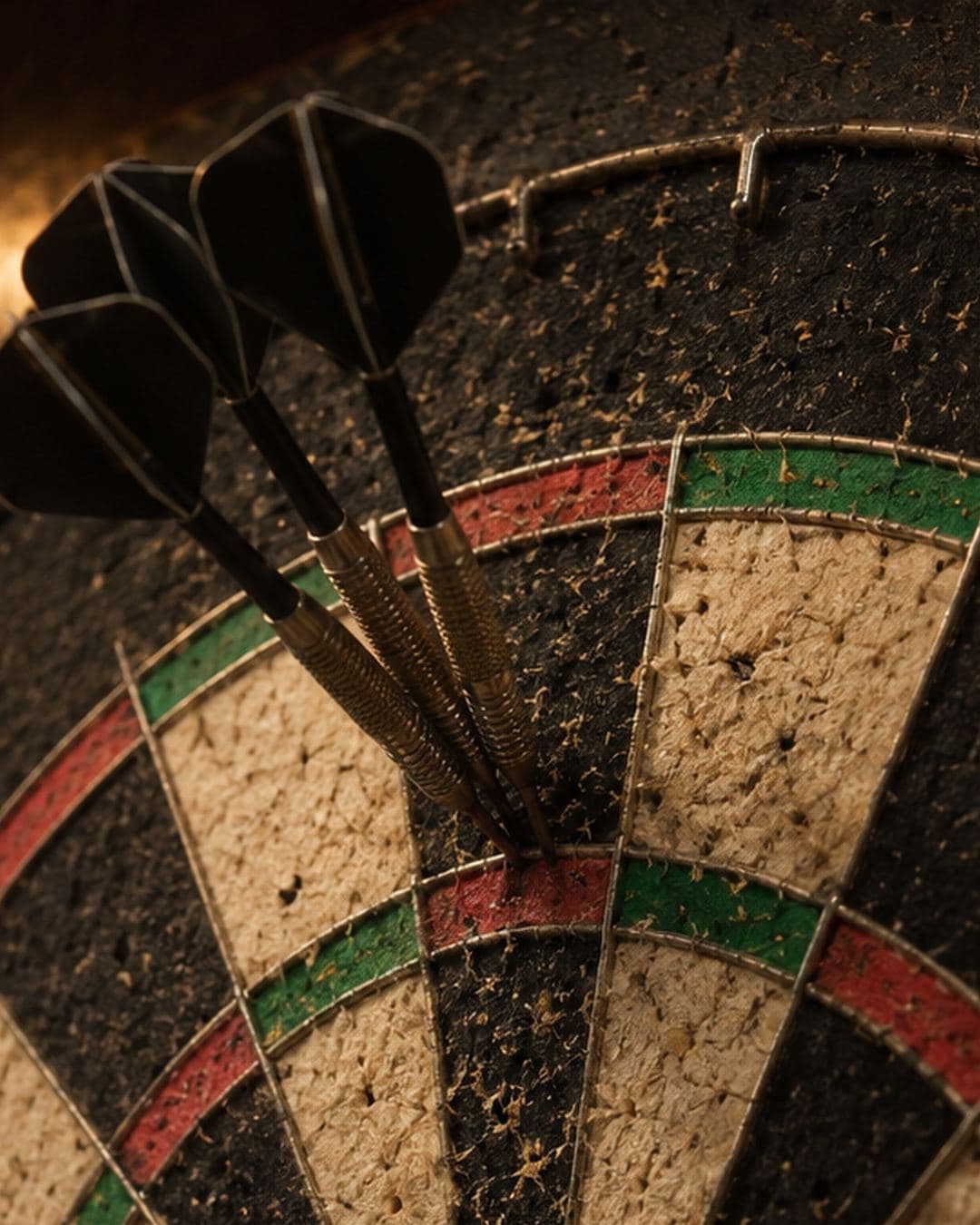 Three darts sunk in the treble twenty of a worn bristle dartboard